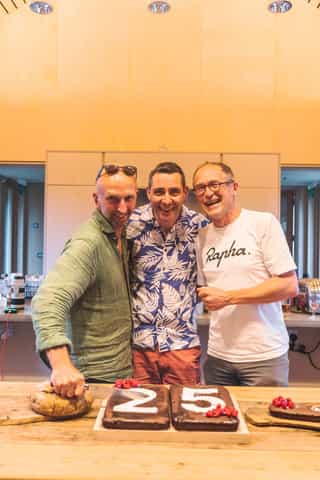 An image of three men smiling for a photograph together, laughing towards the camera