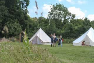 An image of three people chatting standing outside a large tent