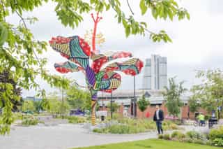 Hibiscus Rising sculpture surrounded by grass planting and lighting.