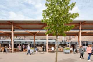 Altrincham outdoor market with new street trees. People are sat in the outdoor seating enjoying food and drink.
