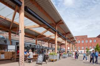Altrincham outdoor market with new street trees. People are sat in the outdoor seating enjoying food and drink.