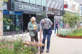 Passers by stop to look at the new seating bench which circles new street SuDS.