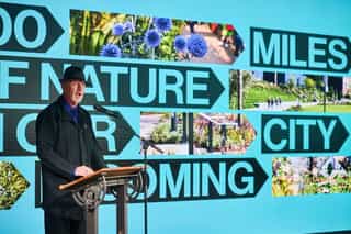 Tom Bloxham presenting to a crowd infront of a big screen with the Cyan Lines branding on