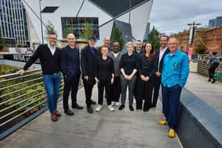 Tom Bloxham and Pete Swift with all of the Cyan Lines Sponsors, stood on a bridge at Factory Aviva Studios in Manchester