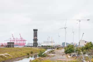 Image showing Liverpool Waters, with the historic clock tower in the distance, wind turbines and a crane.