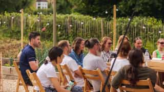 An image of people all gathered sitting on deck chairs, smiling as they listen to someone not pictured