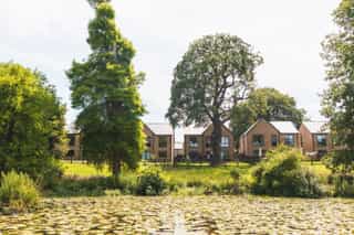 An wide angle image of the Standish Houses from across the lake on site