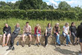 An image of the Planit Team sitting along a stone wall at Camp Standish