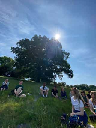 An image of people sitting in a circle on the grass