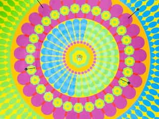 Aerial shot looking down at Yinka Allori lay in the middle of a bright mural painted on the ground